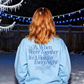 Person wearing a light blue sweatshirt with text in a snowy outdoor setting