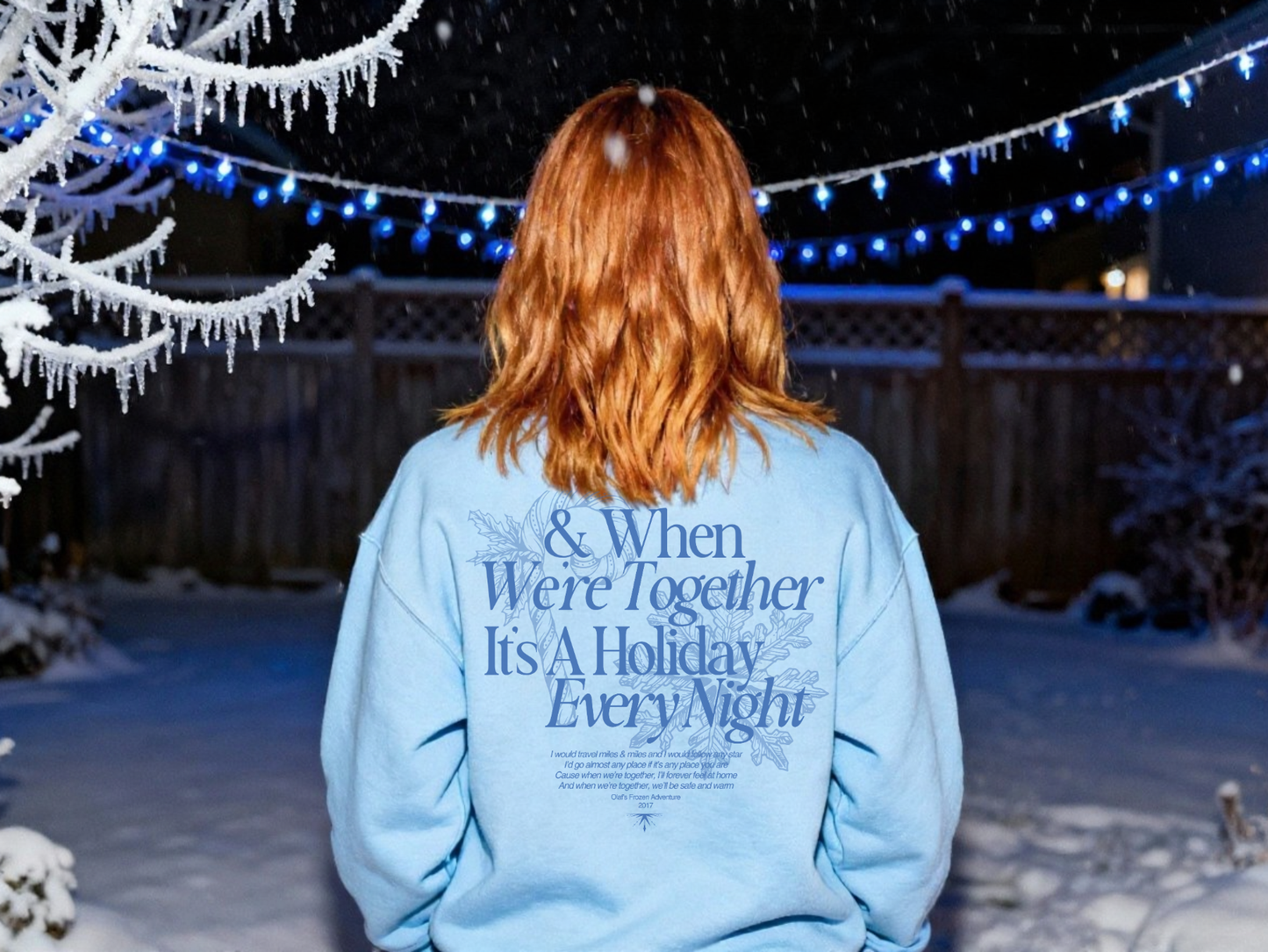Person wearing a light blue sweatshirt with text in a snowy outdoor setting