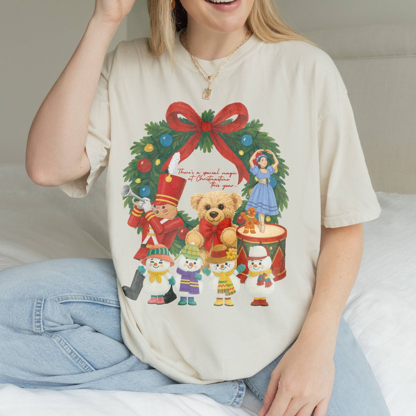 Woman wearing a festive t-shirt with a Christmas design, sitting on a bed.