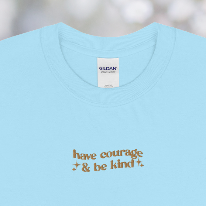 Light blue t-shirt with text on a blurred natural background